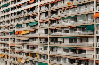 Barselona 'da renkli yağmur örtüsü ve beyaz parmaklıkları olan bir apartman bloğunun eski balkonları