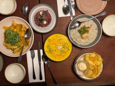 Kabak çorbası, biftekli tart, risotto ve cipsli yemek masası. Kuş bakışı. Yemek için hazır..