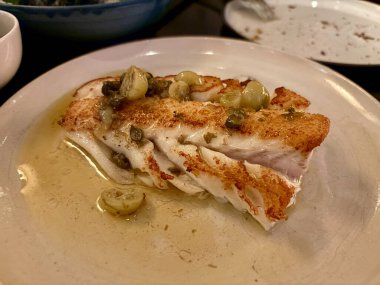 Kızarmış balık filetosu, kapari ve yeşil domatesli Atlantik morina balığı. Yemek için hazır..