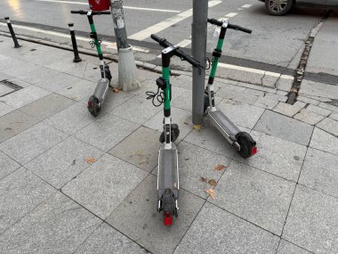 Kiralık, yakın plan, seçici odak, sığ derinlik için caddeye park edilmiş elektrikli scooterlar. Kullanmaya hazır