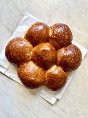 Yumuşak, tereyağlı dokusunu gösteren Brioche ekmek dilimi, kaliteli bir yemek fotoğrafı için temiz bir yüzeye yerleştiriliyor, kabarık iç ve altın kabuğunu vurguluyor. Yemek hazır.