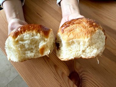 Yumuşak, tereyağlı dokusunu gösteren Brioche ekmek dilimi, kaliteli bir yemek fotoğrafı için temiz bir yüzeye yerleştiriliyor, kabarık iç ve altın kabuğunu vurguluyor. Yemek hazır.