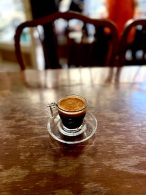 Kahve dükkanının ahşap masasında cam bardakta kahve. 