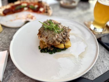 Restoran masasında patates, ıspanak ve meyve ile servis edilen güzel ızgara tavuk butları.