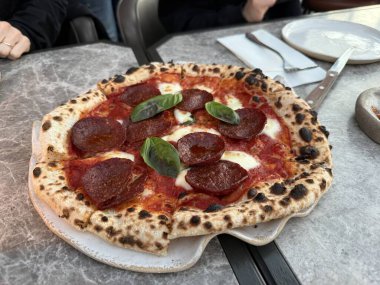 Restoranda fesleğenli pepperonili pizza. Yemek hazır.