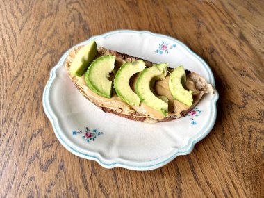 Avokado ve fıstık ezmeli tost tahta masada. Yemek hazır.