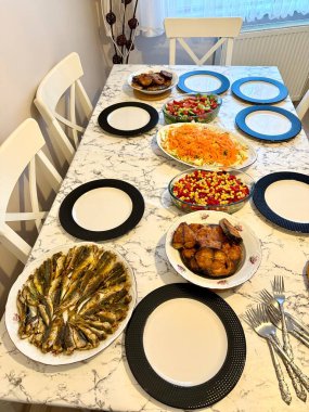 Büyük bir aile, taze balık bonito palamut ve ançüezli istavrit salatasıyla yemek yer.