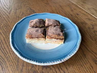 Traditional Turkish dessert cold baklava in the plate. Geleneksel Soguk baklava on wooden table. clipart