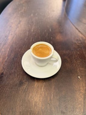 Bir fincan kahve espresso, ahşap masada, yakın çekim. İçmeye hazır.