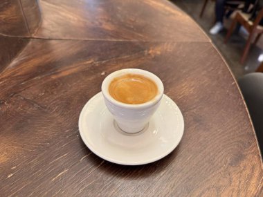 Bir fincan kahve espresso, ahşap masada, yakın çekim. İçmeye hazır.