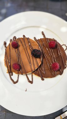 Tabakla servis edilen ahududulu krep ve çikolata sosu. Yemek hazır.