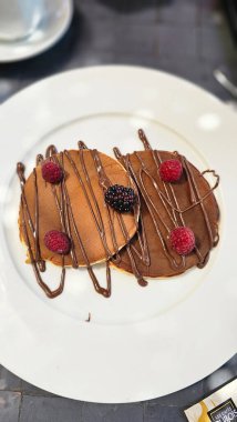 Tabakla servis edilen ahududulu krep ve çikolata sosu. Yemek hazır.