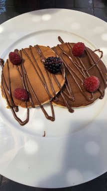 Tabakla servis edilen ahududulu krep ve çikolata sosu. Yemek hazır.