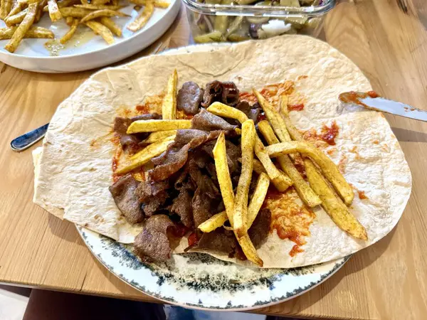 Beef Doner, Shawarma 'yı ahşap masaya sardı. Tabakta Arap ve Türk sokak yemeklerini yakından görüyor.