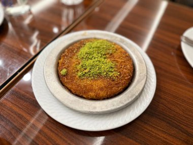 Orta Doğu tatlıları kunefe kunafa kadayif şam fıstıklı Türk Arap geleneksel tatlısıyla pudra ve peynir fıstıklı Türk tatlısı kunafa ya da konafa şekeri sunulursa kaday.