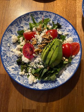 Avokado, vişneli domates ve ahşap masada ceviz salatası.