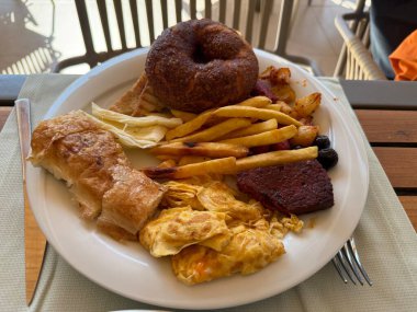 Fırın, çörek ve patatesle servis edilen sağlıksız kahvaltı tabağı.