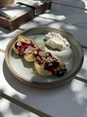 Krem soslu ve yabanmersinli süzme peynirli krep. Syrniki yemeye ve servis etmeye hazır.