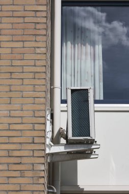 Bir evin dış duvarına monte edilmiş modern hava kaynağı ısı pompası sürdürülebilir, çevre dostu bir şekilde ısıtma ve soğutma için enerji tasarrufu teknolojisi sunuyor..