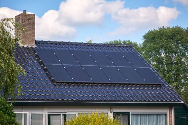 Yerleşim yerlerinin çatısına kurulmuş güneş panelleri, yenilenebilir enerjinin modern yaşama entegrasyonunu gösteriyor. Gündelik ortamlarda sürdürülebilir enerji çözümlerinin bir gösterimi