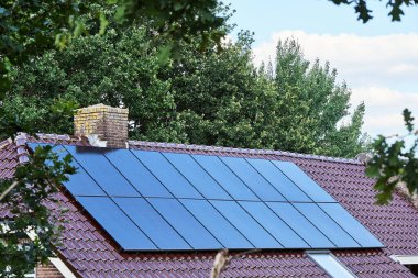 Yerleşim yerlerinin çatısına kurulmuş güneş panelleri, yenilenebilir enerjinin modern yaşama entegrasyonunu gösteriyor. Gündelik ortamlarda sürdürülebilir enerji çözümlerinin bir gösterimi