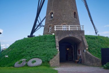 Nuenen 'deki tarihi yel değirmeni de Roosdonck' un zemin katı manzarası. Giriş mağarası ve çimlerin üzerinde duran eski değirmen taşları.