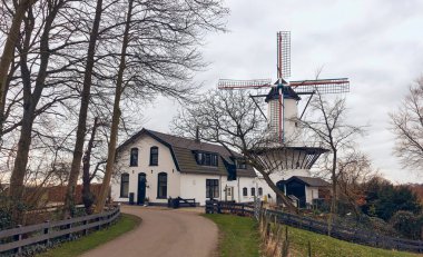 The historic windmill De Vlinder in Deil, Netherlands, surrounded by greenery, showcasing Dutch heritage, architecture, and a serene rural landscape. clipart