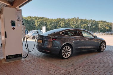 11 Ağustos 2022: Hollanda 'da yenilenebilir enerji: Tesla yazın bir gölgelik altında benzin istasyonunda şarj oluyor.