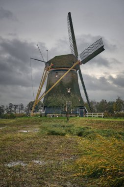 Loenderveense polder değirmeni, tarihi bir drenaj kanalı, çevresi yeşilliklerle çevrili, Hollanda su yönetimi mirası sergileniyor..