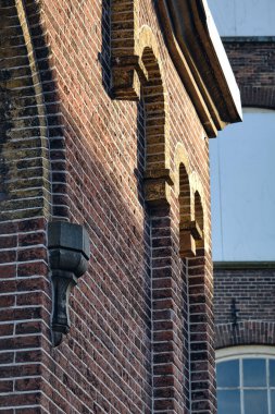 A charming historic facade in Kampen, Netherlands, featuring stained glass windows, yellow and black details, and a traditional street lamp. clipart