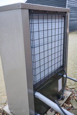 Kışın verimli ısıtma için sürdürülebilir enerji teknolojisi sunan bir yerleşim bölgesinde HVAC ısı pompası ünitesi.