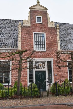 29 Aralık 2024 - Eelde / Hollanda: Eelde 'de yeniden inşa edilen Nijsinghhuis Portakalında yemyeşil bir bahçe, eğreltiotu, sarmaşık ve bulutlu bir kış ortamında gökyüzü altında tuğla bir duvar.