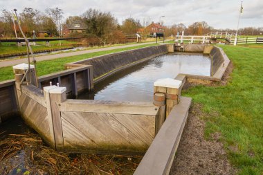 Picturesque lock in Buitenweg polder, Oud-Zuilen, Utrecht, featuring wood construction, clear water, and green surroundings under a cloudy sky. clipart