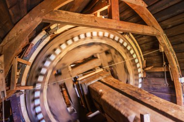 Historic Kockengse Windmill: Interior view of a traditional Dutch windmill showcasing wooden wheel, brake, cogs and gears at speed, surrounded by rustic wooden construction details. clipart