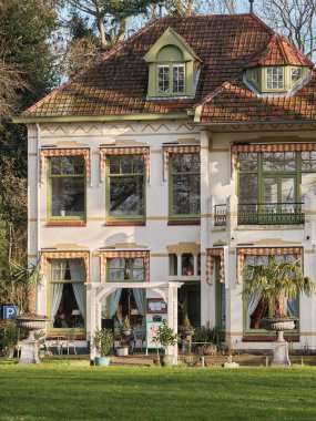 2 Şubat 2025 - Echten, Drenthe, Hollanda: Beyaz cepheli tarihi bir villa, süs saksıları ve verandalı yeşil bahçe bitkileri.