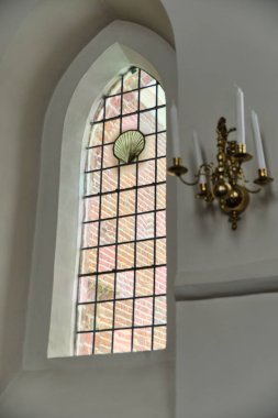 February 12, 2025 - Rolde, Netherlands: The interior of Jacobus Church featuring an  stained glass window and chandelier. clipart