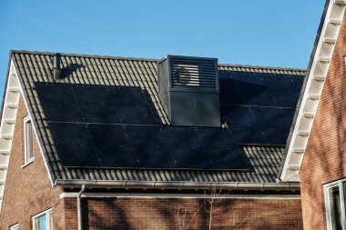 Assen, Hollanda 'da modern, enerji tasarruflu bir ev çatıda entegre ısı pompaları, güneş panelleri ve açık mavi gökyüzü var..