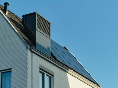 Assen, Hollanda 'da modern, enerji tasarruflu bir ev çatıda entegre ısı pompaları, güneş panelleri ve açık mavi gökyüzü var..