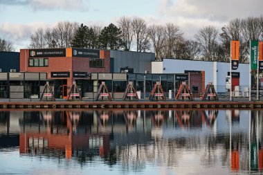 1 Mart 2025 - Assen Hollanda: Havenkwartier 'deki sakin liman havzası BMN şirketi yumuşak akşam ışığında inşaat malzemeleri satıyor.