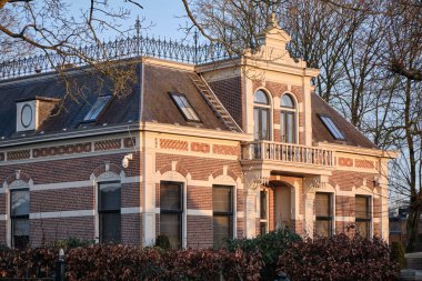 2 Mart 2025 - Borger, Hollanda: Borger 'in ana caddesinde dekore edilmiş tuğla cepheli, süslü detayları ve küçük bir balkonu olan tarihi bir malikane.