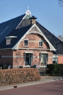 6 Mart 2025 - Kollummersweach - Hollanda: Friesland 'da kırmızı tuğlalı, fayanslı çatı ve ahşap oymalı geleneksel Frizya çiftlik evi.