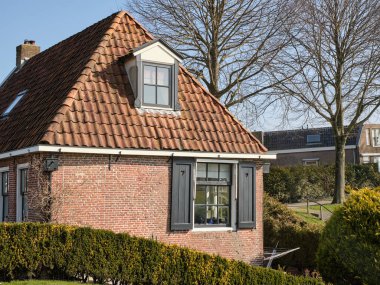 6 Mart 2025 - Dokkum-Hollanda: Dokkum 'daki yel değirmeni Zeldenrust' un yanındaki tarihi gişe tahsildarları evi, eskiden gristmill 'de vergi kontrolü için kullanılıyordu.