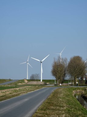 10 Mart 2025 - Uithuizermeeden, Hollanda: Kendi rüzgar türbini ve eski deniz çukurunun arkasındaki rüzgar çiftliği. Hollanda 'da yenilenebilir enerji üretimi.