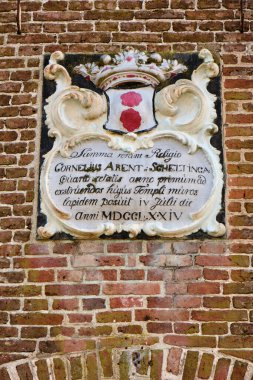 4 Mart 2025 - Tsjaard, Hollanda: Geleneksel bir saat, kemerli pencereler ve ağaç dalları tarafından çerçevelenmiş tarihi tuğla içeren tarihi kilise.