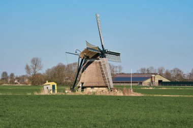Tarihi Kimswerder Mill ve modern mandıra çiftliği, arka planda güneş panelleri, Friesland, Hollanda, kırsal bir alanda geçmiş ve geleceği harmanlıyor..