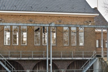 8 Mart 2025 Ezumazijl - Hollanda: Eski sahil geçidi siluetleri ve asma köprü gün batımında Friesland, Ezumazijl kırsalında.