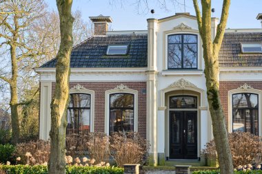 4 Mart 2025 - Wirdum, Hollanda: Süslü cepheli, büyük pencereli ve siyah kapılı geleneksel malikane, bir zamanlar köy noteri veya papazına ev sahipliği yapıyordu..