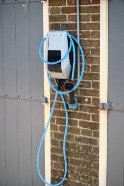 21 Nisan 2025 - Hollanda Puttershoek: Tuğla garaj duvarına monte edilmiş elektrikli araç şarj istasyonu, Hollanda 'nın tarihi yerleşim bölgesindeki yerel EV altyapısını gösteriyor.