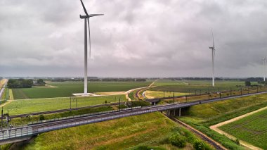 27 Mayıs 2025 - Moerdijk-Hollanda: Moerdijk 'in açık kırsalındaki rüzgar türbinlerinin yakınındaki yüksek hızlı demiryolunun altından geçen bir demiryolu lokomotifi.