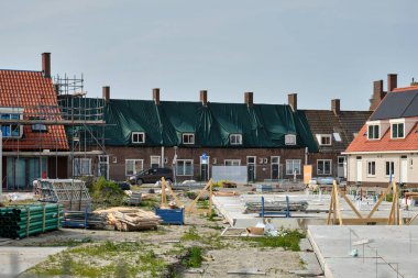 1 Haziran 2025 - Middelburg-Hollanda: Asbest çatı kaldırma işlemi sırasında yeşil tenteli sosyal konutlar, yeni konut geliştirme sahasının önünde.